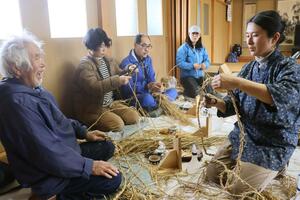 鬼太鼓で使うわらじを編む参加者＝佐渡市千種