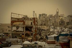 　壊滅したガザの市街地と、砂嵐に見舞われた仮設テント＝１３日（ゲッティ＝共同）