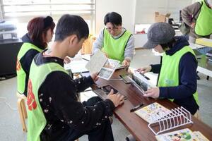 　被災した写真の分類作業をする「チーム北リアス（写真班）」のメンバー＝３月、岩手県野田村