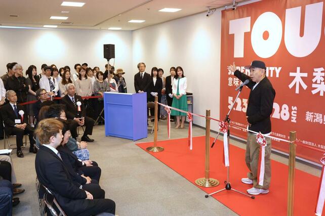 来場者の前でオープニングセレモニーのあいさつをする木梨憲武さん＝２３日、新潟市中央区の県民会館