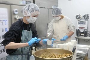 納豆菌を振りかけた大豆をカップに詰める折原奈帆さん（左）＝佐渡市上新穂