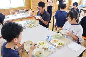生産者と葉月みのりの新米を食べる新道小の児童たち=柏崎市新道