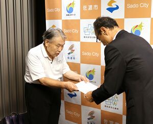 渡辺竜吾市長(右)に、報告書を提出する入浴施設あり方検討会の西川会長=9月10日、佐渡市役所