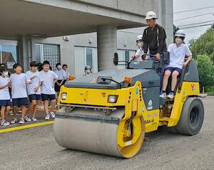 道路を舗装する重機に体験乗車した糸魚川中の生徒=糸魚川市