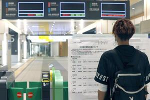 運休を知らせる掲示板を確認する通勤通学客ら=9月20日、JR新潟駅