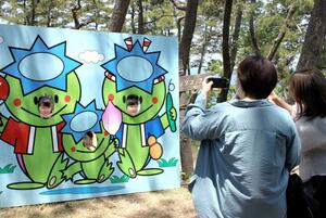 かっぱの看板で記念写真を撮る家族連れ＝６月１日、上越市大潟区四ツ屋浜