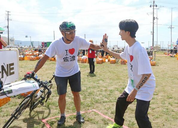 バイクを終えた渡辺竜五・佐渡市長から、ランの「けえ【島育ち】」さんへのバトンタッチ＝９月１日、佐渡市