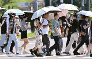 真夏のような強い日差しの下、日傘を差す人たち=6月28日、東京都千代田区