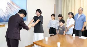 チャリティーコンサートで集めた義援金を寄付する小中学生ら=三条市役所