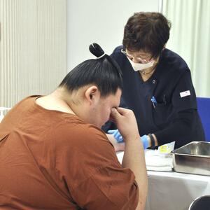 健康診断で、採血時に目を閉じる大相撲の大関大の里(左)=2月7日、東京・両国国技館