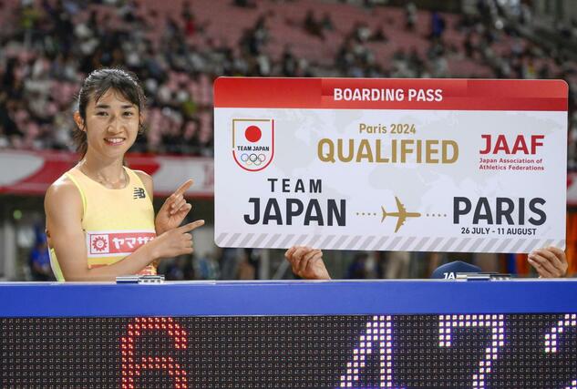 女子１５００メートルでパリ五輪の代表に決まり、ボードを指さし笑顔の田中希実＝デンカビッグスワン