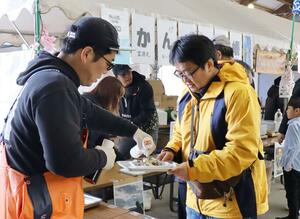 佐渡特産のカキを使った料理などを味わう来場者＝１４日、佐渡市両津湊