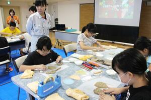 貝殻や竹串で模様を付けながら土器型プレートを作る児童ら=燕市水道町1