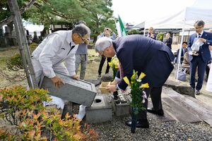 イタリア大使館で採取した土を堀部安兵衛の墓に納めるジャンルイジ・ベネデッティ大使(手前右)=新発田市大栄町2
