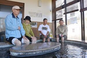 岩室温泉の特長である「黒湯」に足を浸して、楽しむ観光客＝１０月３０日、新潟市西蒲区のいわむろや