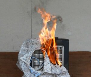 電気ストーブに落下した衣類から出火する再現実験の様子