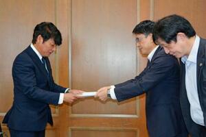 佐賀県議会議長(左)に要望書を提出する県弁護士会の半田望弁護士(右手前)ら=1日午前、佐賀市