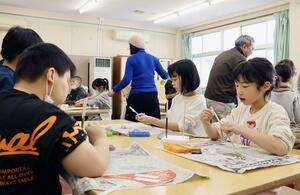 三条仏壇の職人による出前授業で、蒔絵や錺金具の技術を体験する子どもたち=三条市西潟