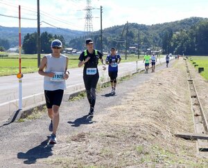 田園地帯を駆ける「えちご・くびき野100キロマラソン」の参加者=10月13日、上越市吉川区