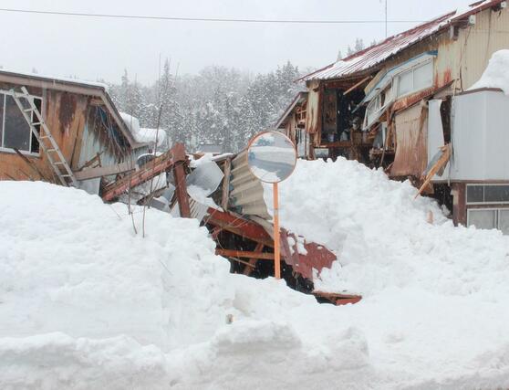 雪の重みで倒れた車庫。隣の住家部分も損壊していた＝３日、柏崎市与板