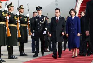 4日、中国・北京の空港に到着した韓国の李在明大統領と妻の金恵景氏(聯合=共同)
