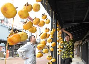 雁木の軒下に柿をつるす大町小の児童ら=10月18日、上越市大町5