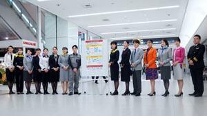 モバイルバッテリーの取り扱い変更を周知するポスターと航空各社の社員ら=14日午後、羽田空港