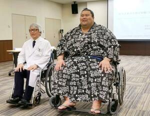 体重300キロまで対応できる超特大の車いす(右)に試乗する現役最重量の三段目出羽ノ城さん=11日午前、名古屋市