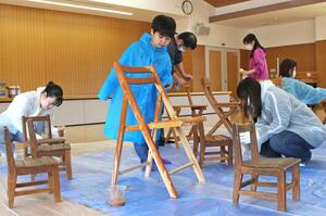 通学路に設置する見守り用の椅子を塗装する子どもたち=6日、新潟市秋葉区