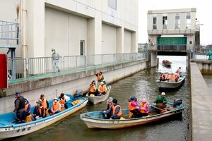 新井郷川排水機場の船通しゲートを漁船で通過する参加者=新潟市北区濁川