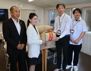 児童養護施設にコメを寄贈する田中産業の田中萌監査役(左から2人目)=上越市御殿山町