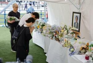 安倍元首相銃撃事件から3年、現場付近に設置された献花台で手を合わせる人たち=8日午前、奈良市