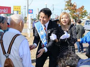 街頭演説に集まった有権者に握手をして回る米山隆一(中央)と妻の室井佑月(右隣)=10月18日、見附市