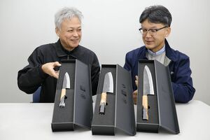オリジナルブランド「庖斬巴」の包丁を展開する金井産業の金井孝夫社長(右)と片桐信幸さん。手前の包丁は右から牛刀、三徳、ペティナイフ=三条市月岡1