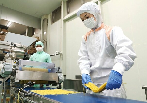県産米粉入り生パスタの製造風景。仕上がり具合を入念に確認する=胎内市清水