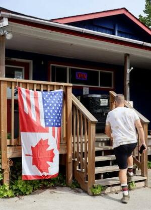 米ワシントン州ポイントロバーツの店舗前にある米国旗とカナダ国旗を組み合わせた旗。カナダからの訪問者に友好を示すため店が掲げた=5月(共同)