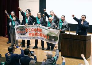 勝訴を願い拳を上げる原告ら=4月13日、新潟市中央区の万代市民会館