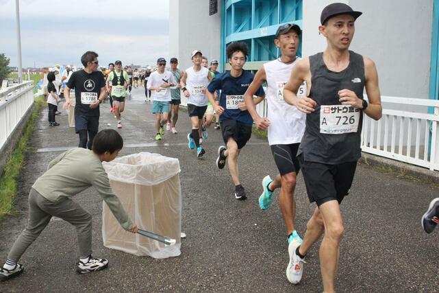 
ランナーが捨てた使用済みの紙コップを拾い集める子どもの姿もみられた＝12日正午ごろ、新潟市西区
