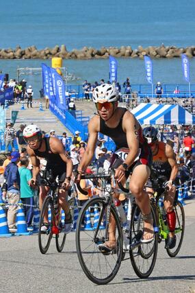 バイクで坂道を駆け抜ける選手たち＝村上市瀬波温泉１
