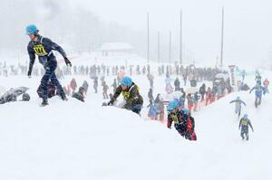 雪が降りしきる中、雪壁を必死に乗り越える出場者=10日、十日市松代の市松代総合体育館グラウンド周辺