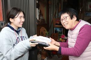 高齢者におせち料理を手渡す小須戸中の生徒＝３０日、新潟市秋葉区