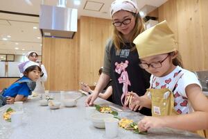 笹の上の上越産米に好きな具材を載せる親子連れ=上越市西本町3