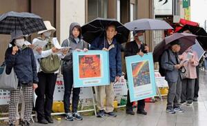 　空襲連の集会で被害が描かれたパネルを掲げる参加者ら＝２３日午後、東京都台東区