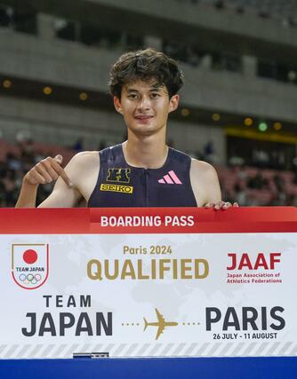 男子４００メートル障害でパリ五輪の代表に決まり、ボードを手に笑顔の豊田兼＝デンカビッグスワン