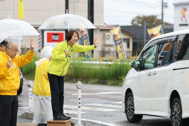 通勤者に手を振る菊田真紀子さん＝三条市