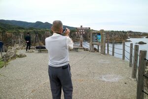 新潟県への「里帰り」で佐渡の尖閣湾を訪れた男性。趣味のカメラで古里新潟の風景を何枚も記録した=佐渡市北狄
