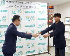 明治安田生命保険の古賀生治新潟支社長(左)から目録を受け取る小林尚史さん=6月13日、新潟市中央区