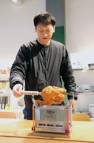 サンプルの丸焼き肉を使って、新商品のローストスタンドを紹介する山谷産業社長の山谷武範さん=三条市北入蔵2