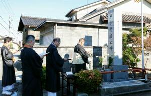 「模擬原爆」の犠牲者を追悼する式典で、慰霊碑の前で読経する僧侶=26日朝、富山市