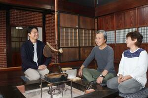 東夢のオーナー夫妻と囲炉裏を囲んで談笑する鎌田一さん(左)=佐渡市山田